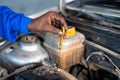 close up shot of Car mechanic hands inspecting engine oil level of car at garage - concept of maintenance service, blue