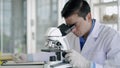 Young scientist man looking through microscope in laboratory