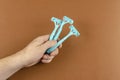 Handholds light blue plastic razors on a brown background Royalty Free Stock Photo