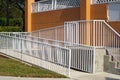 Handicap ramp with white railing and orange wall