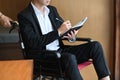 Handicapped business man in wheelchair holding pen and writing some information on notebook.