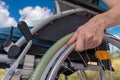 Handicapped disabled man sitting on wheelchair outdoors in meadow