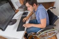 Handicapped disabled man on wheelchair is working with computer in office