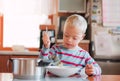 A handicapped down syndrome child pouring soup into a plate indoors.