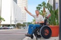 Handicapped man in a wheelchair hailing a taxi in the city