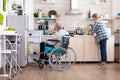 Handicapped man in wheelchair opening refrigerator and helping wife preparing breakfast Royalty Free Stock Photo