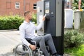 Handicapped Man In Wheelchair Paying For Car Parking Ticket Royalty Free Stock Photo