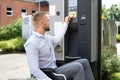 Handicapped Man In Wheelchair Paying For Car Parking Ticket Royalty Free Stock Photo