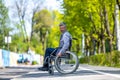 Handicapped man in wheelchair riding on street road, outdoor leisure for disable guy.