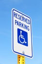 A handicapped parking sign against a blue sky.