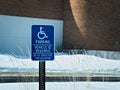 Handicapped parking sign posted in snow covered parking lot Royalty Free Stock Photo