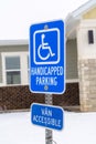 Handicapped Parking and Van Accessible sign against snow and building in winter Royalty Free Stock Photo