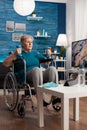 Handicapped senior woman holding trainer dumbbells doing arms exercise