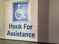Handicapped symbol on sign stating Honk For Assistance