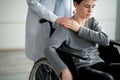 Handicapped teenage boy in wheelchair feeling depressed, nurse taking care of him at home, copy space Royalty Free Stock Photo