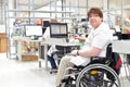 handicapped worker in a wheelchair assembling electronic components in a modern factory at the workplace Royalty Free Stock Photo