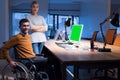 Handicapped young man with female colleague working in office. Disabled businessman in the wheelchair works in the office at the