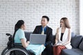 Handicapped young woman talking with colleagues using laptop computer in office. Disabled business executive on wheelchair using l Royalty Free Stock Photo
