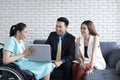 Handicapped young woman talking with colleagues using laptop computer in office. Disabled business executive on wheelchair using l Royalty Free Stock Photo