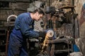 Handicraftsman processes a blacksmith`s tool on a power grinding wheel