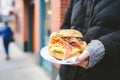 handing over a breakfast bagel sandwich outside a cafe