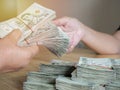 Handing over stacks of Thai banknote to other hand with soft light background