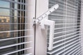 A handle and a restrictor, window stopper or limiter on PVC double glazed window with horisontal aluminium blinds close up Royalty Free Stock Photo