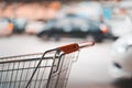 Handle of shopping cart and blurred car at parking lot Royalty Free Stock Photo