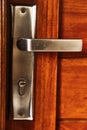 Handle with stainless steel lock on a brown wooden door. Royalty Free Stock Photo