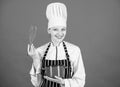 Handling kitchen tasks with ease. Professional cook smiling with pot and whipping tool in kitchen. Cute kitchen maid