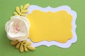 handmade artificial beige flower and shiny yellow leaves on a green paper background and two curly sheets of yellow and white pape Royalty Free Stock Photo