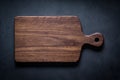 Handmade black walnut wood cutting board on the dark tabletop. Royalty Free Stock Photo