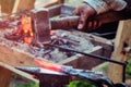 Handmade blacksmith at the forge on the outdoor. Hammer blows on the iron disc on the anvil. Forging sword blades retro weapons