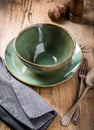 Handmade bowl and plate of green color with vintage spoon and fork on wooden background. Royalty Free Stock Photo