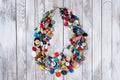 Handmade bright colored jewelry made of plastic buttons on white wooden background.
