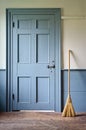 Handmade Broom Beside Vintage Blue Door in Old House