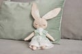 Handmade bunny toy sitting on sofa and wearing lace dress