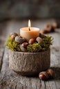 Handmade candle holder crafted from acorns and moss, featuring a lit candle, set on rustic wooden surface, creating a warm and Royalty Free Stock Photo