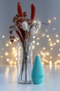 Handmade candle on a table with dry flowers in a vase. Lights in background. Cozy home decor. Royalty Free Stock Photo
