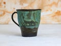 Handmade ceramic cup with bubbled turquoise glaze, firing defects, blistered surface texture Royalty Free Stock Photo