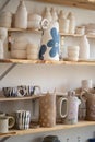 Handmade ceramic cups, jugs, jars and vase on shelves in craft pottery kitchenware store or workshop Royalty Free Stock Photo