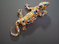 Handmade ceramic toy decorative lizard made of colorful small ceramic tiles on dark grey background for home interior design