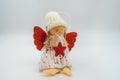 Handmade Christmas angel doll, red wings, knitted cap, star, red heart, dress, blond braids, cheerful face, golden shoes Royalty Free Stock Photo