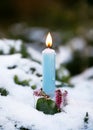 Handmade Christmas candle holder made of ice, pink calluna blossom branches with burning blue candle in the snow covered garen. Royalty Free Stock Photo