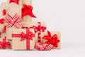 Handmade christmas gifts boxes of kraft paper, christmas tree with festive red ribbons and bows closeup on white wood background. Royalty Free Stock Photo