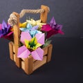 Handmade colored paper flowers origami bouquet paper craft art in a basket with grass in the studio on colored