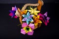 Handmade colored paper flowers origami bouquet paper craft art in a basket with grass in the studio on darkbackground