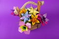 Handmade colored paper flowers origami bouquet paper craft art in a basket with grass in the studio on colored pink