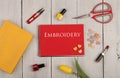 Handmade concept - sewing scissors, tulip, red note pad with text embroidery, yellow book, nail polish, lipstick and buttons in