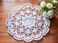 Handmade crochet white lace napkin on table with flowers in living room